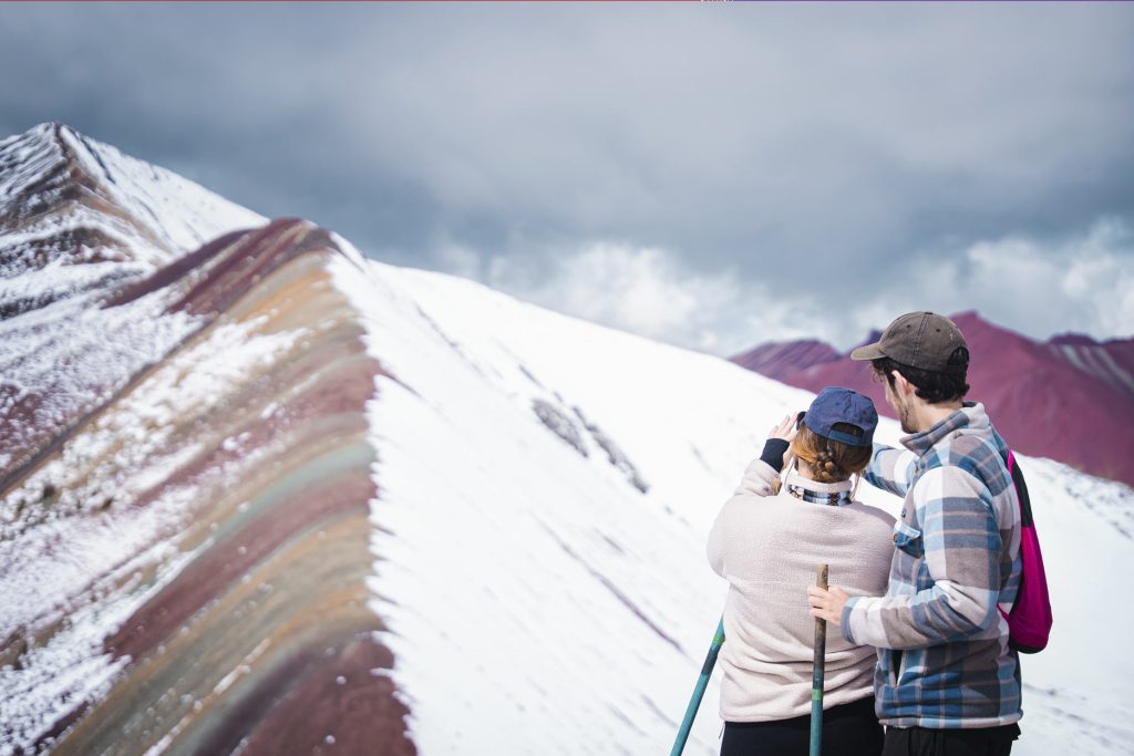 Couple looking out over a snowy Rainbow Mountain (Vinicunca)