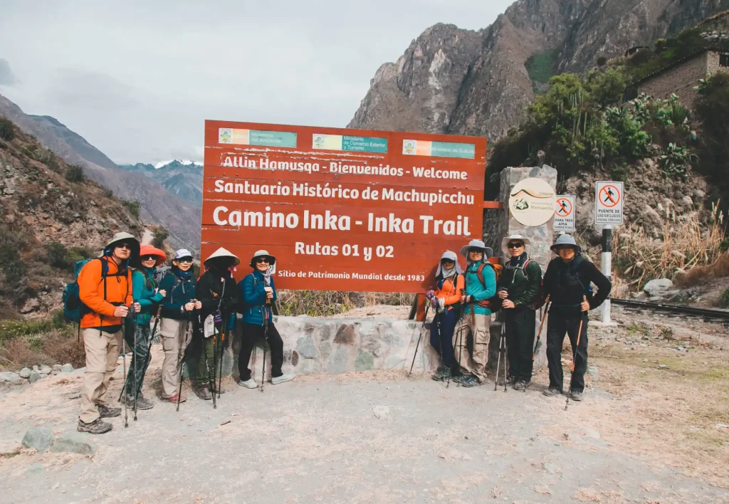Group of tourists with their guide at the famous km 82 sign at the start of the Inca Trail to Machu Picchu