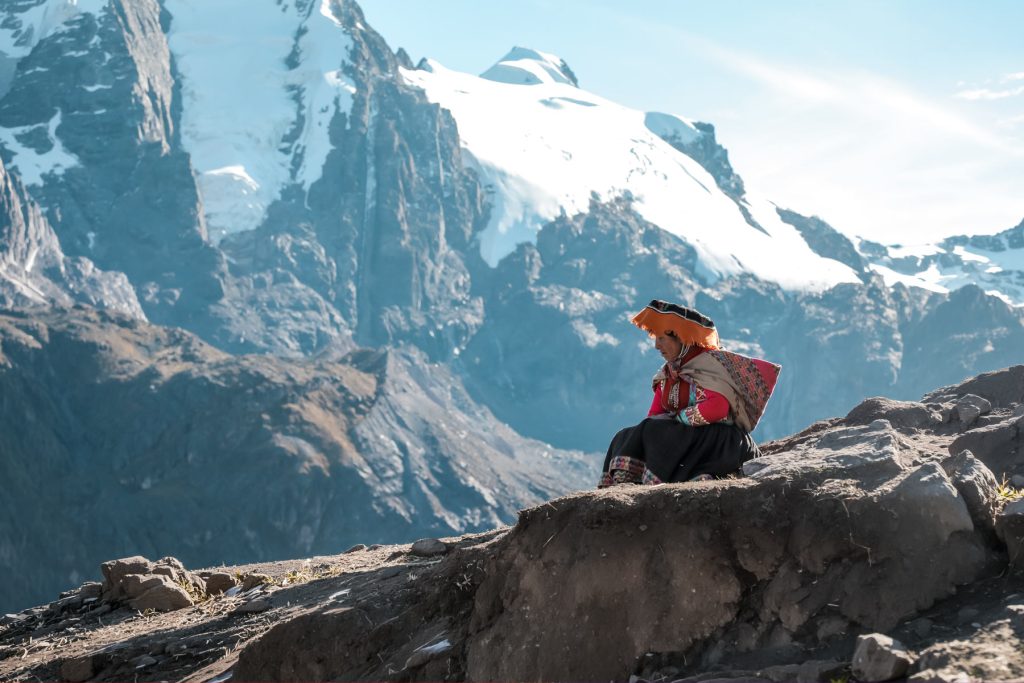 Local woman sitting beside mountains.
