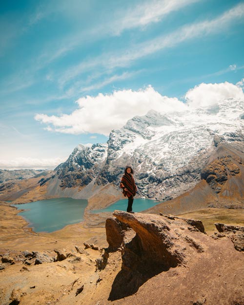 Tourist wearing an Andean poncho standing with the Ausangate mountain in the background